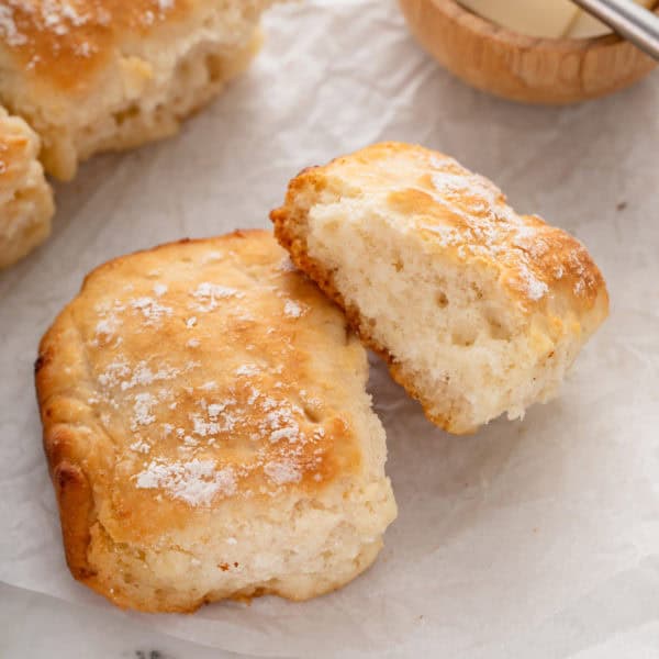 Two 7up biscuits on a piece of parchment paper.