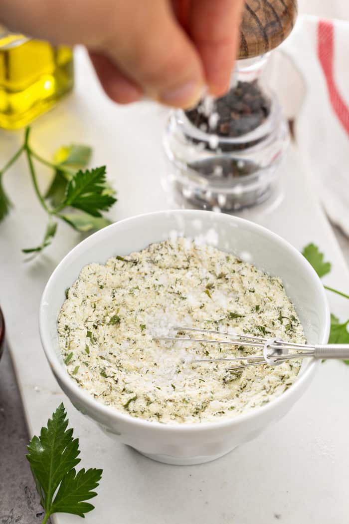 Sea salt being added to a bowl of ranch seasoning mix