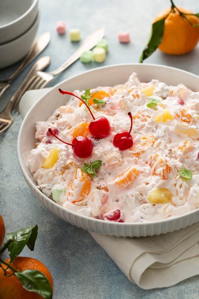 Ambrosia topped with three maraschino cherries in a white serving bowl