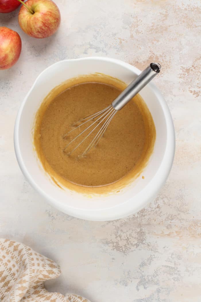 Wet ingredients for apple cider blondies being whisked in a white bowl.