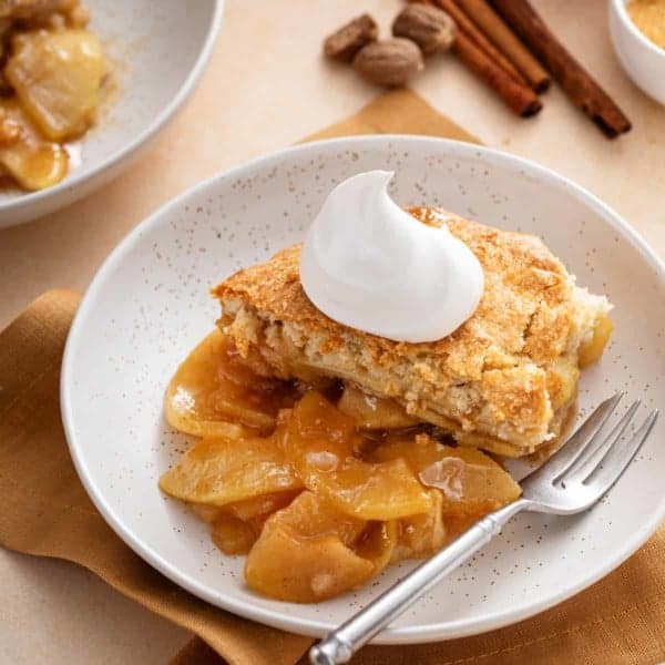 Bowl of apple cobber with whipped cream.