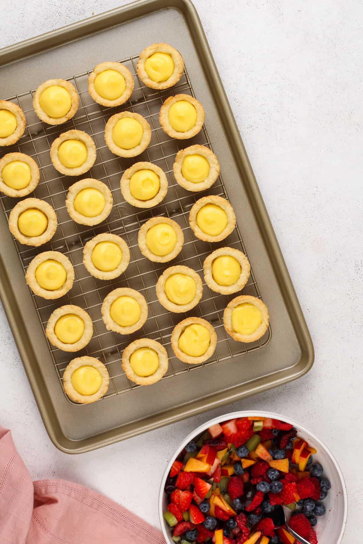 Mini fruit tarts shells filled with vanilla pudding, ready for fruit to be added.