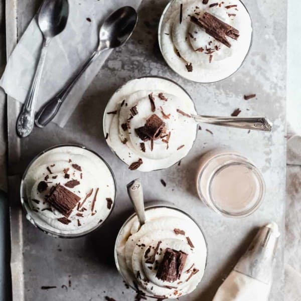 Homemade chocolate pudding in small glass dishes, topped with whipped cream and chocolate shavings