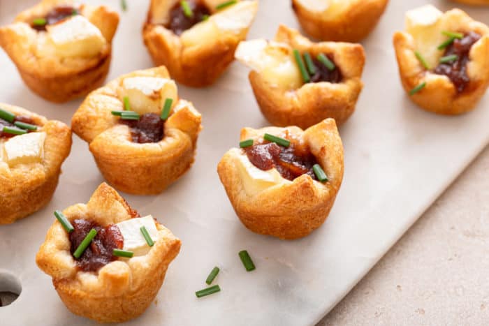 Apple butter brie bites arranged on a marble platter.