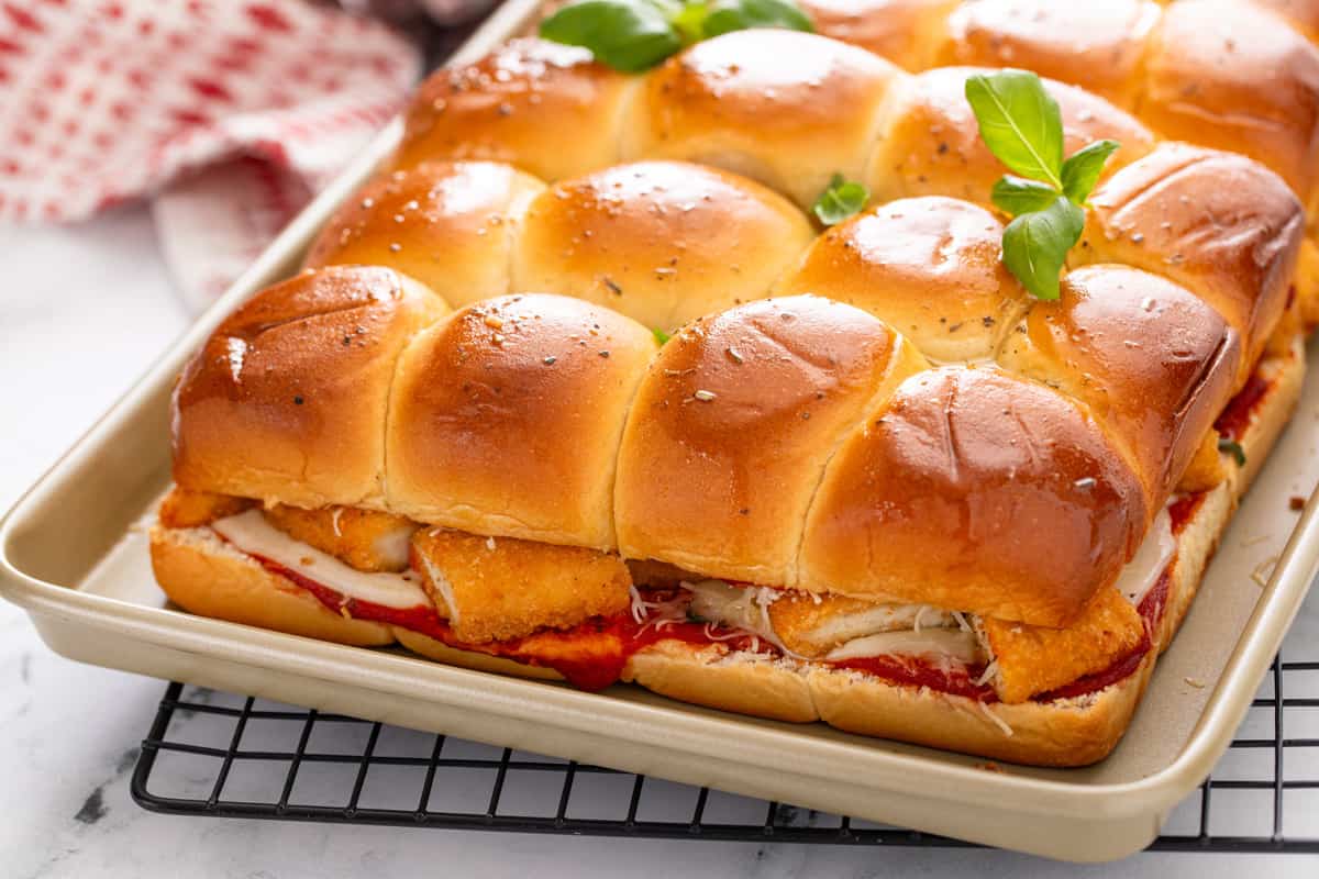 Pan of baked chicken parmesan sliders on a wire rack.