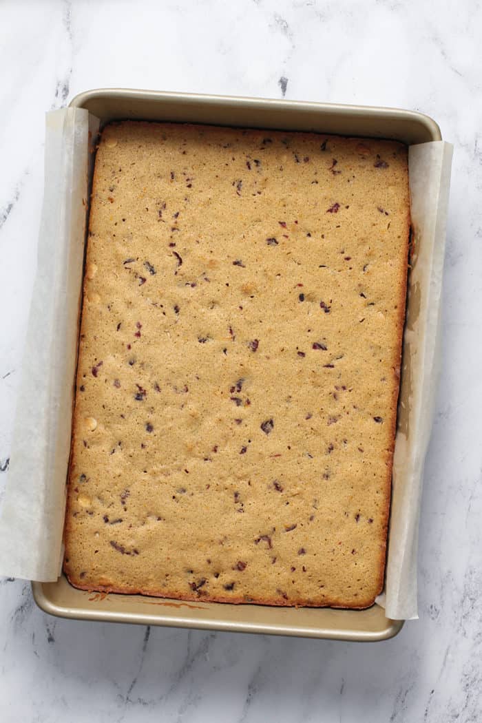 Baked cranberry bliss bars in a parchment-lined baking pan