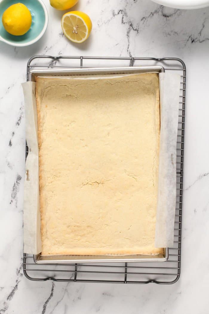 Baked shortbread crust in a metal pan on a wire rack.