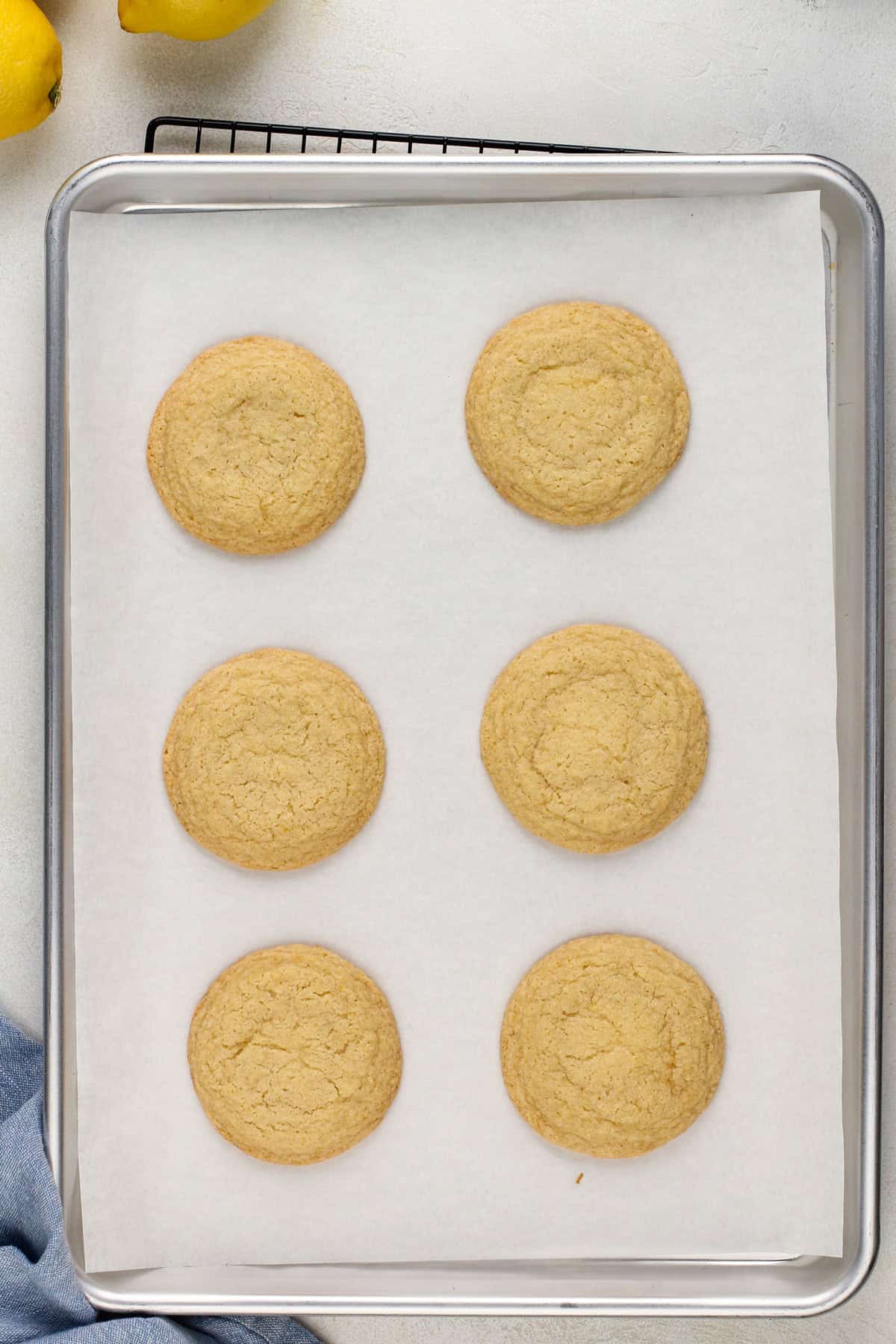 Baked lemon cookies on a parchment-lined baking sheet.