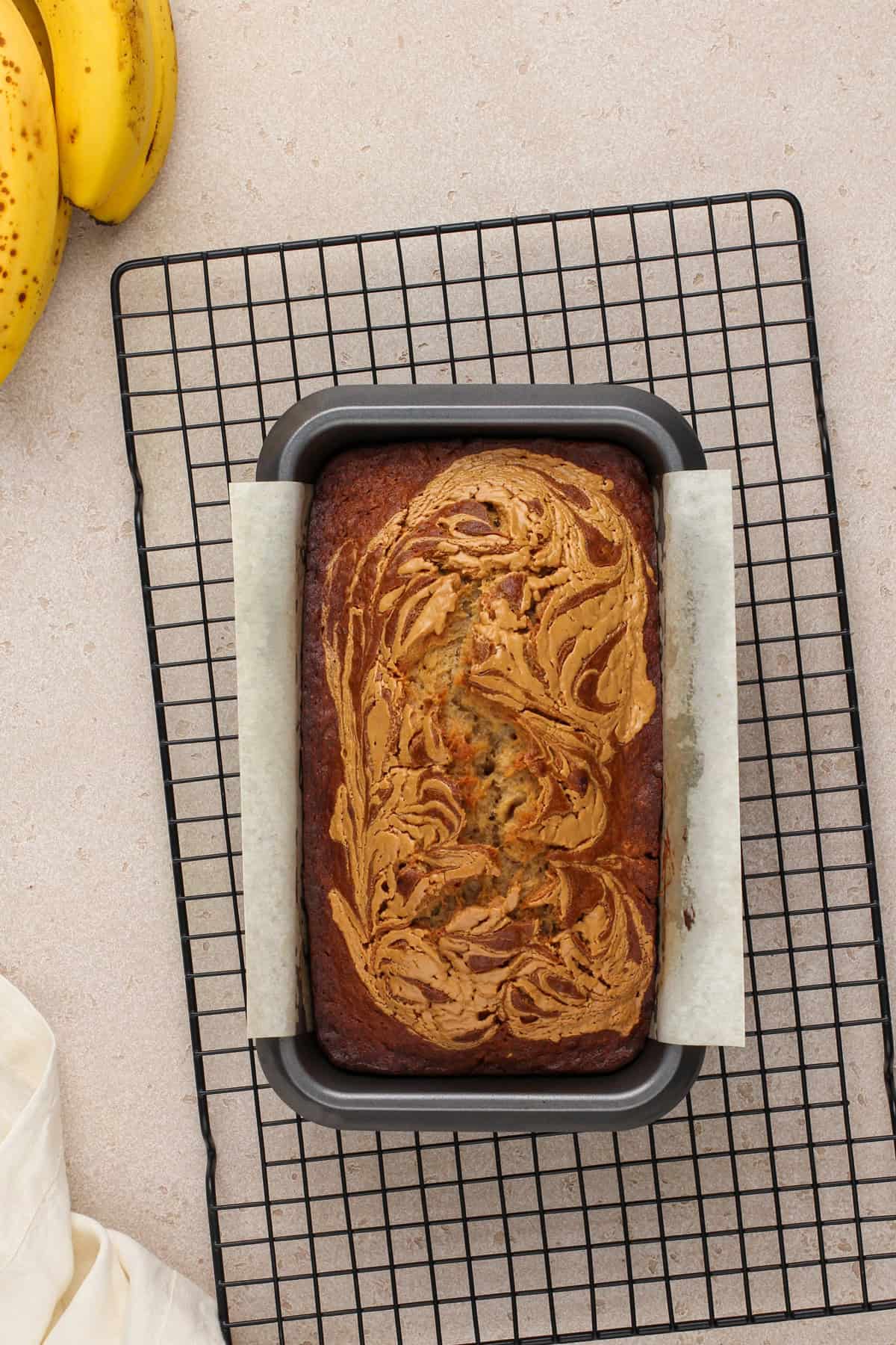 Baked loaf of peanut butter banana bread cooling on a wire rack.