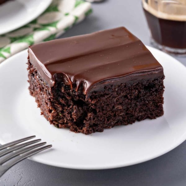 Slice of chocolate zucchini cake with a bite taken out of the corner.