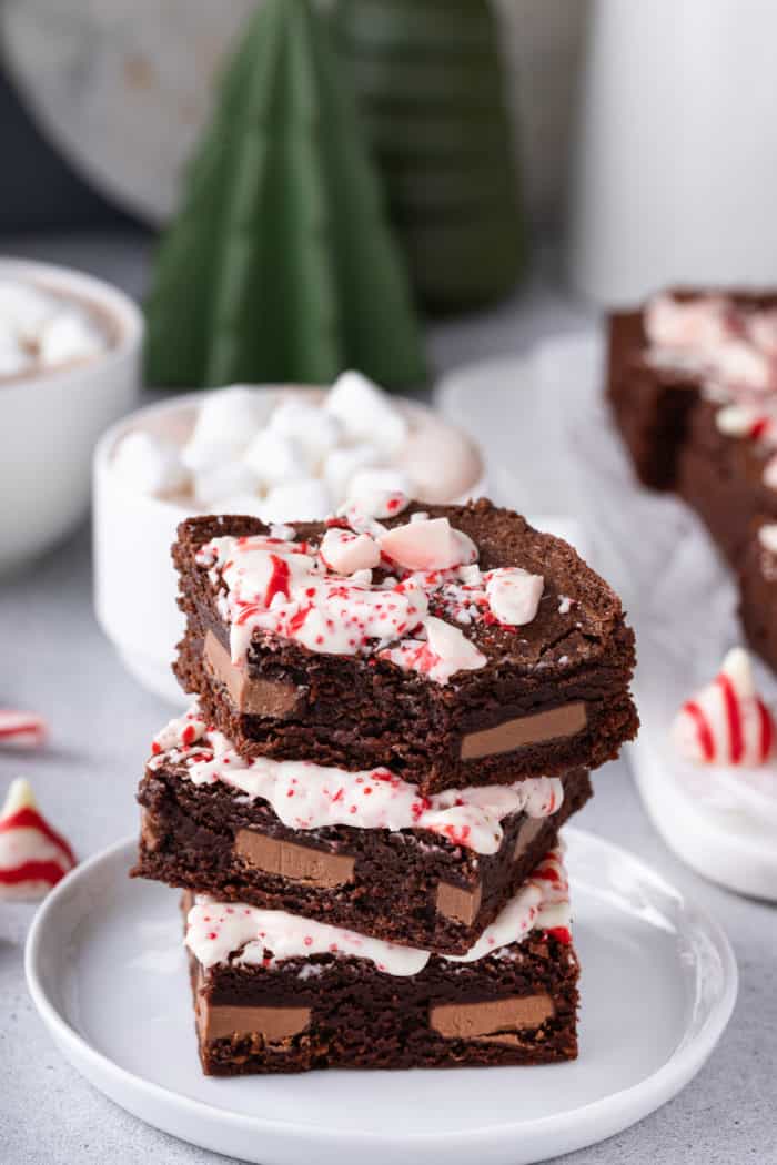 Three stacked peppermint brownies on a white plate. The top brownie has a bite taken out of it.