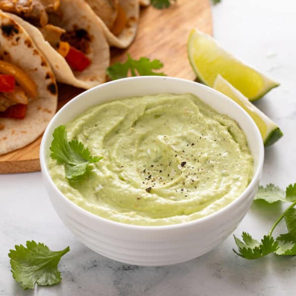 Avocado crema in a white bowl, garnished with cilantro.