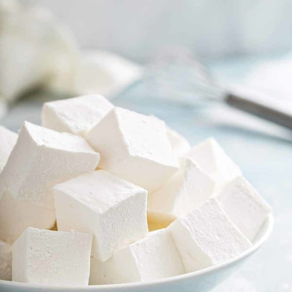 Large white bowl filled with homemade marshmallows on a blue countertop