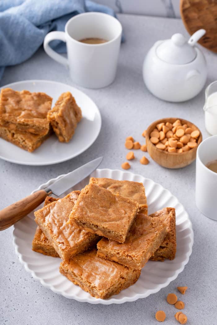 Platter with several brown butter blondies arranged on it. A knife is perched on the side of the platter.