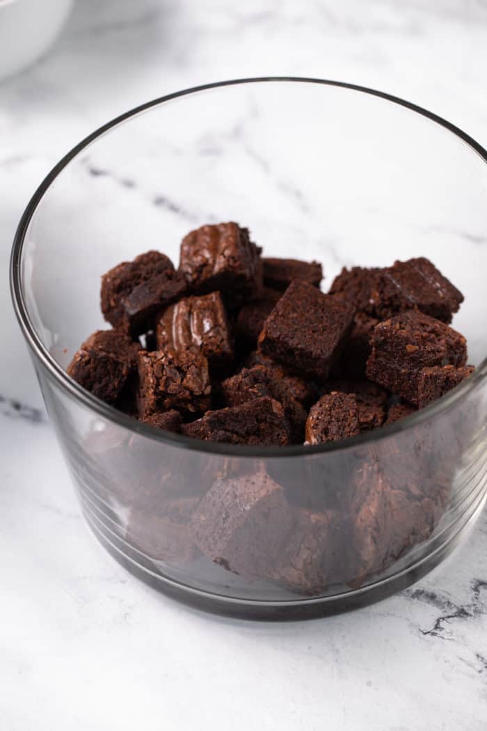 Brownie cubes in the bottom of a glass trifle dish.