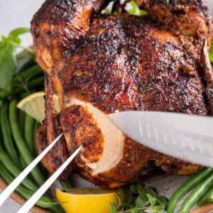 Knife and carving fork slicing a piece of chicken breast from a roasted air fryer chicken.