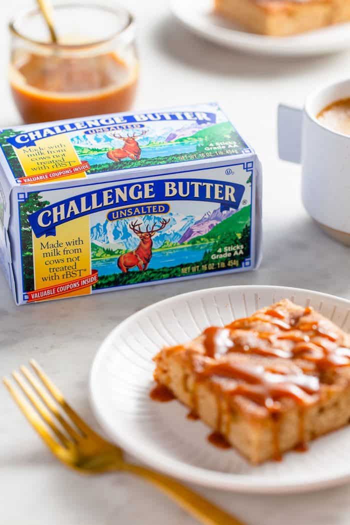 Apple bar drizzled with caramel sauce on a white plate with a package of challenge butter in the background