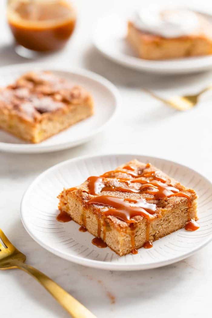 Three white plates with apple bars, each topped with a different topping