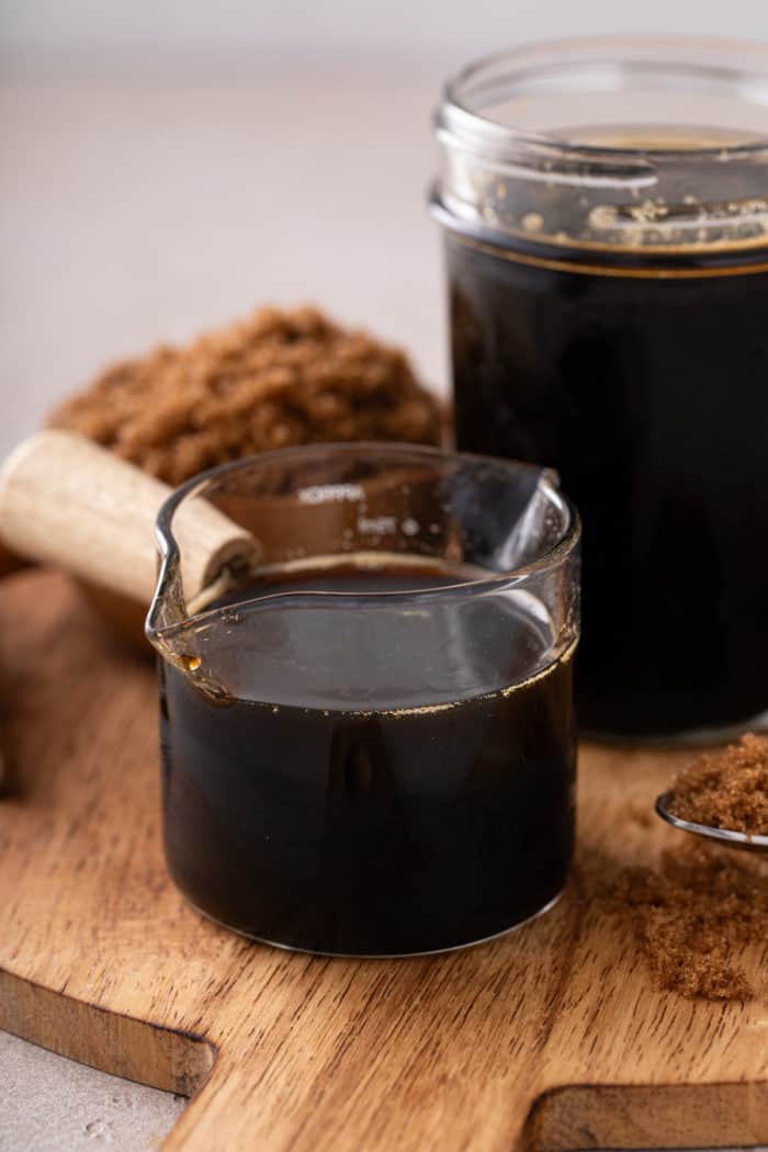 Close up of brown sugar syrup in a glass jar on a wooden board.