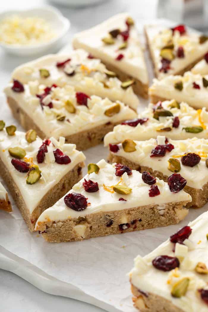 Cranberry bliss bars cut into triangles, set on a piece of parchment paper