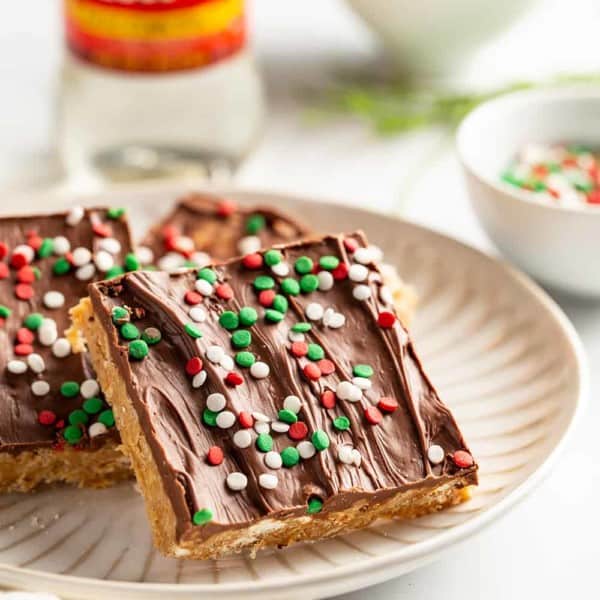 Plated peanut butter pretzel bars with corn syrup and a bowl of pretzels in the background