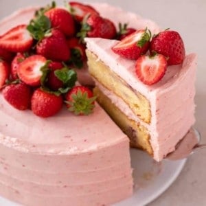 Cake server lifting up a slice of cake from a strawberry layer cake.