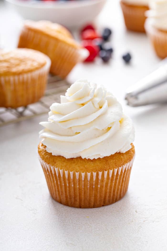 Close up of a vanilla cupcake topped with whipped cream frosting.