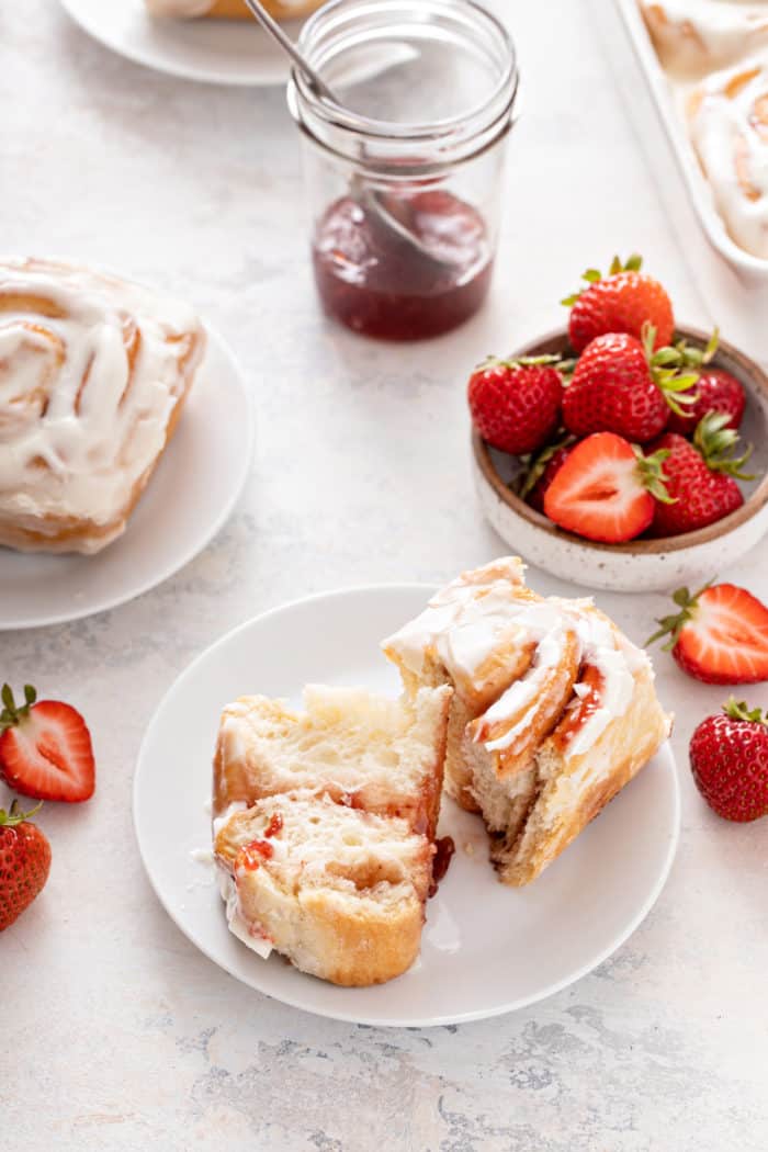 White plate with a halved strawberry sweet roll set on it.