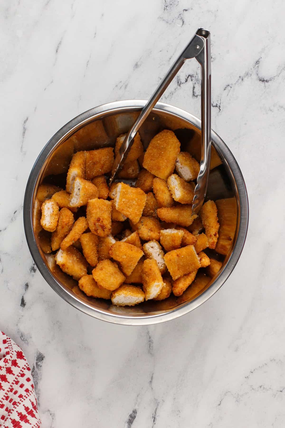 Cut up chicken tenders tossed with italian seasoning in a bowl.