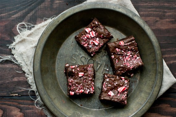 Four dark chocolate candy cane brownies in a metal pie tin on a wood table