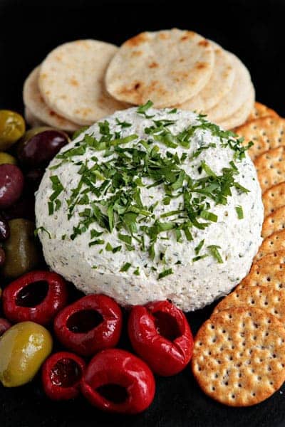 Feta cheese ball next to crackers and olives