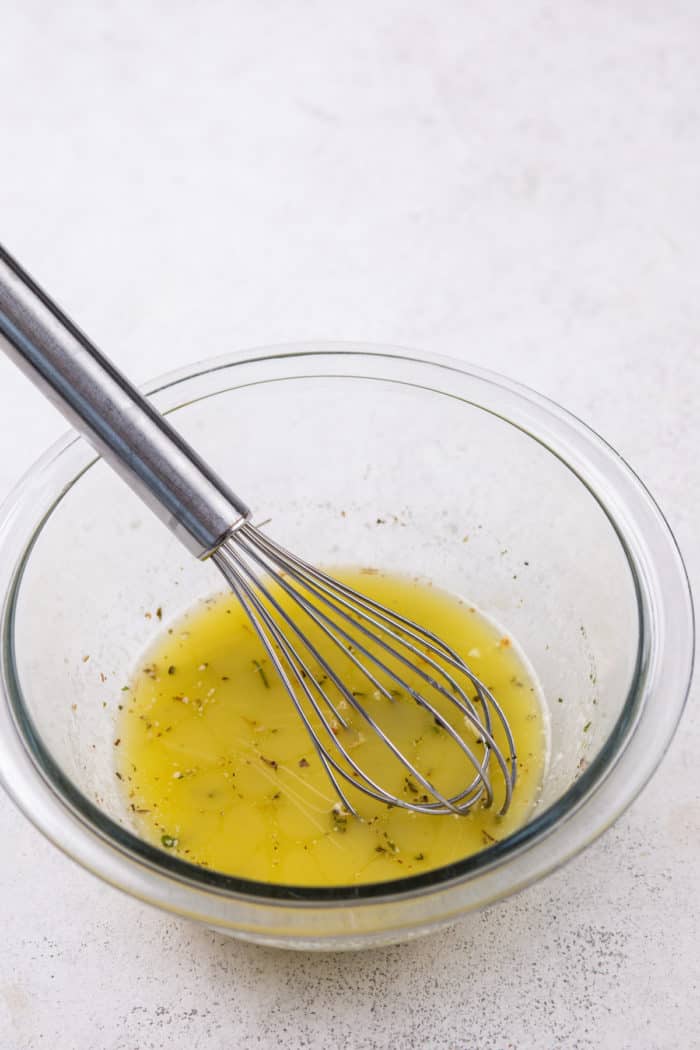 Garlic and herb butter for garlic knots in a glass bowl.