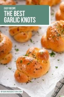 Close up of garlic knots arranged on a piece of parchment paper on top of a wire rack. Text overlay includes recipe name.