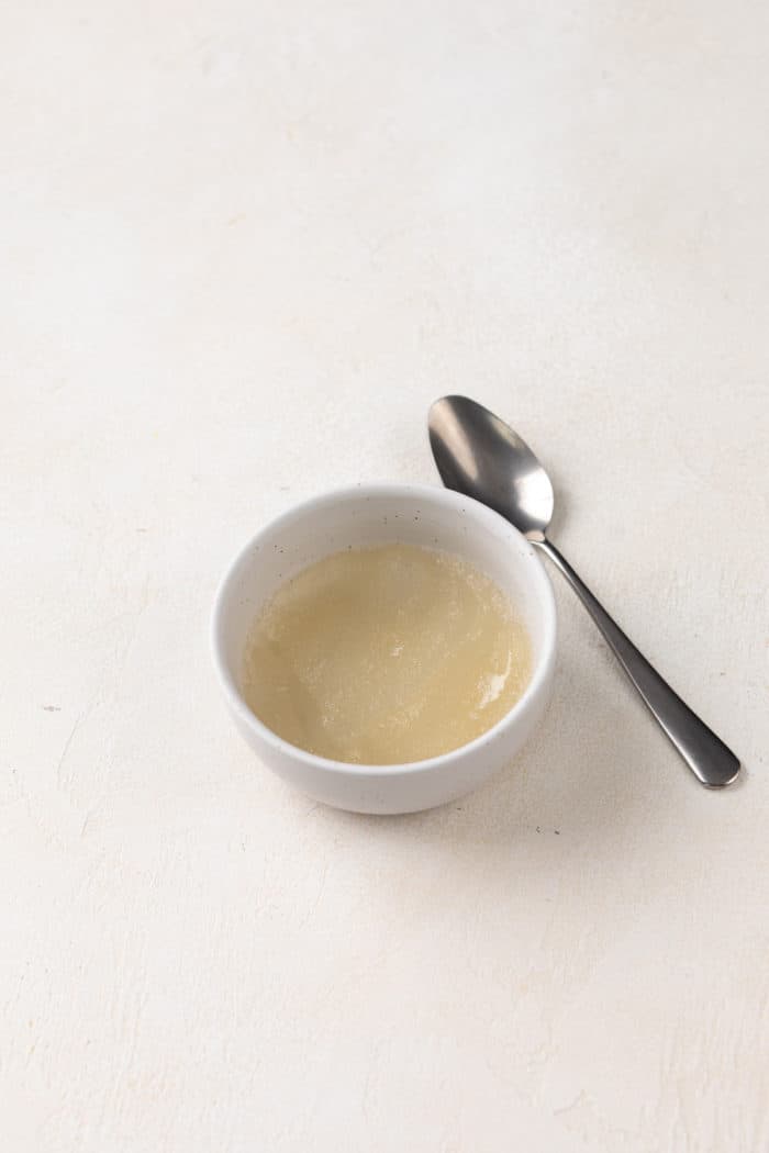 Powdered gelatin bloomed in water in a small white bowl.