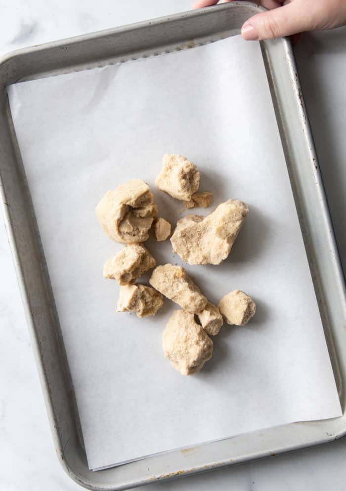 Clumps of hard brown sugar on a parchment-lined baking sheet.