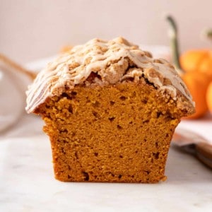 Cross-section view of a loaf of streusel-topped pumpkin bread with maple glaze.