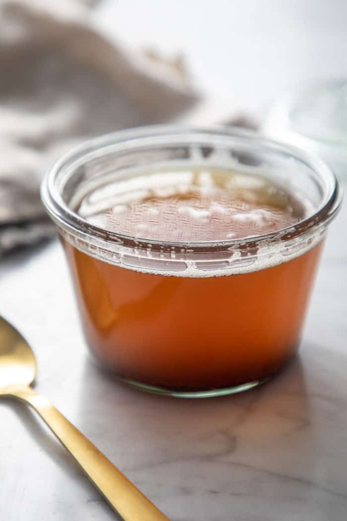 Gold spoon set next to a jar of brown butter on a marble countertop.