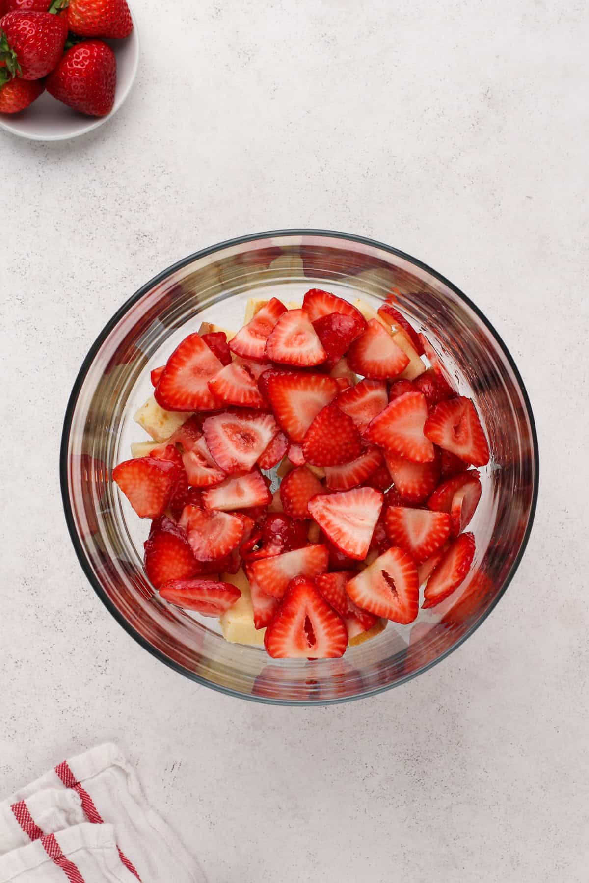 Sliced strawberries layered on top of pound cake cubes in a trifle dish.