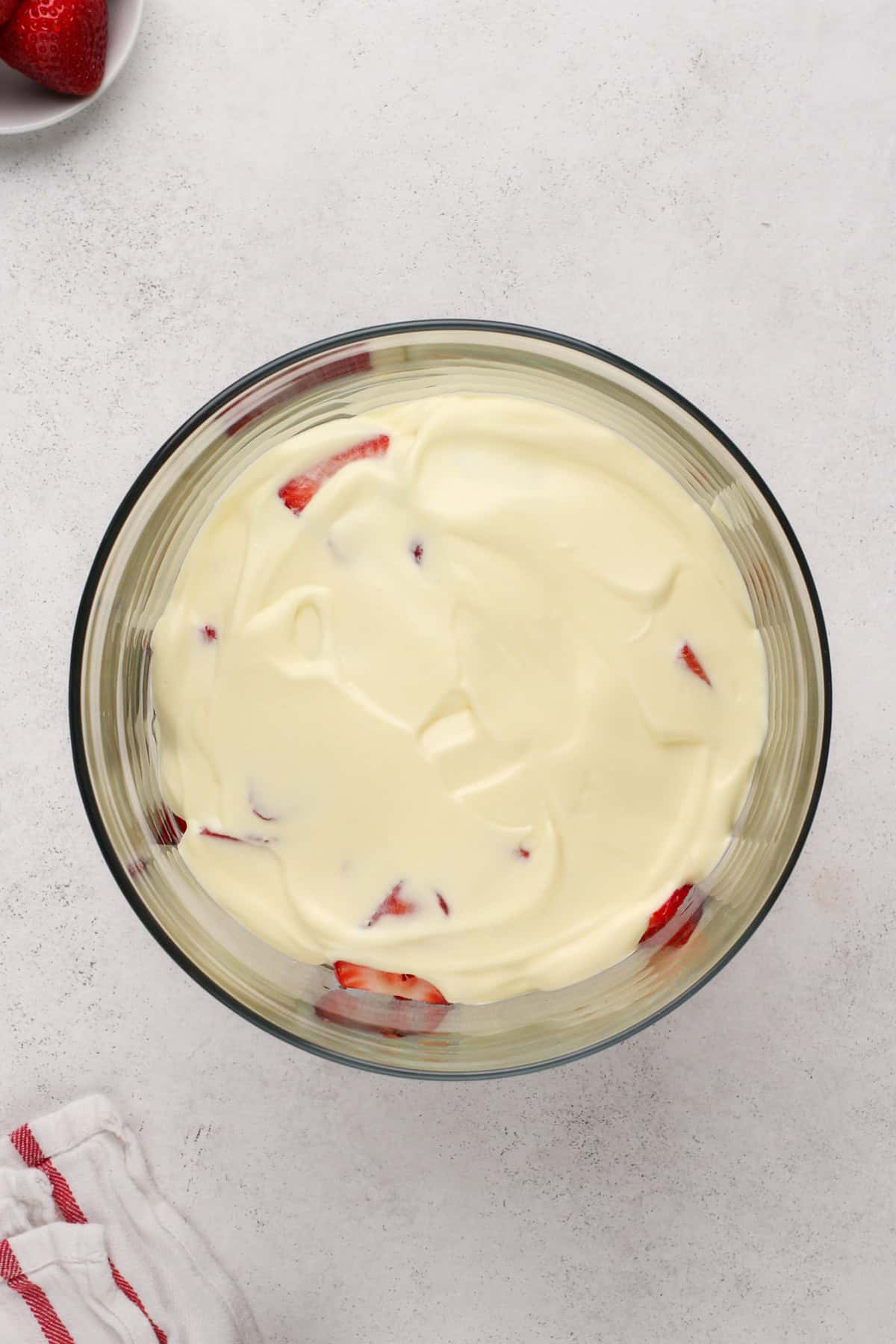 Vanilla pudding layered on top of strawberries in a trifle dish.