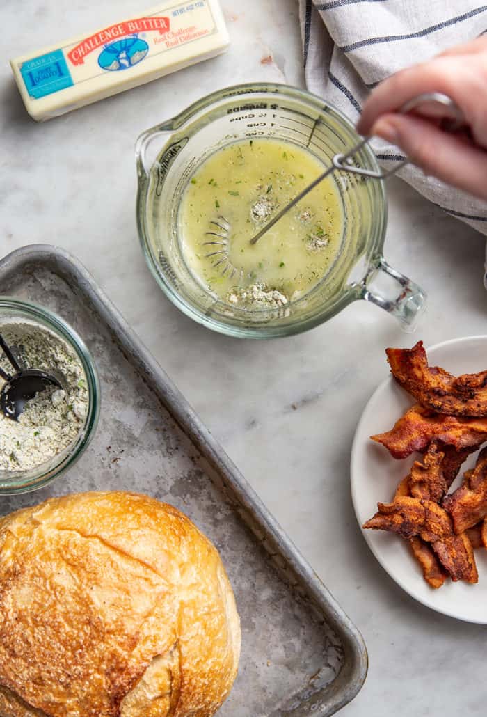 Hand whisking together ranch butter with the ingredients for pull-apart bread around it