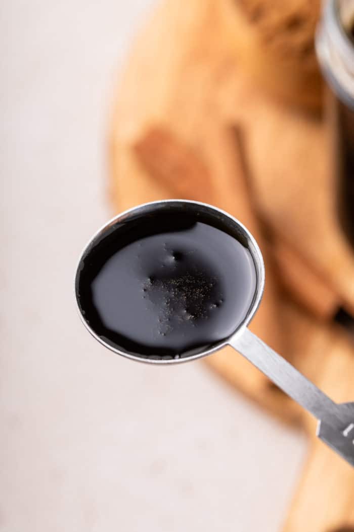 Measuring spoon filled with brown sugar syrup.