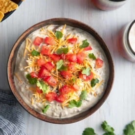 Overhead image of bowl filled with garnished avocado dip.