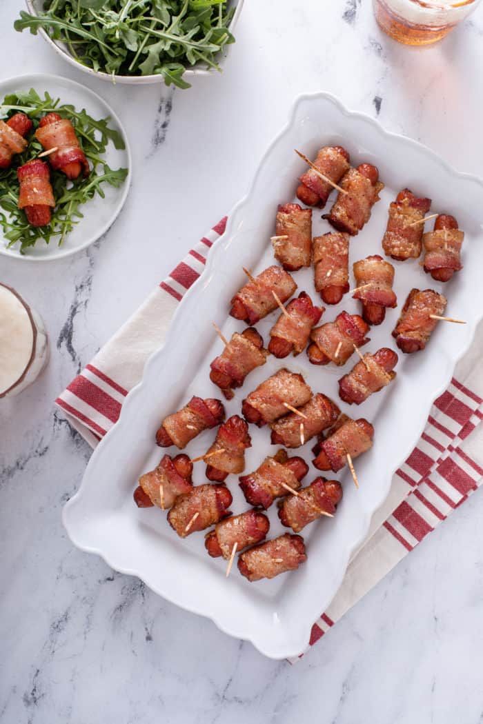 Overhead view of a white platter filled with bacon-wrapped little smokies.