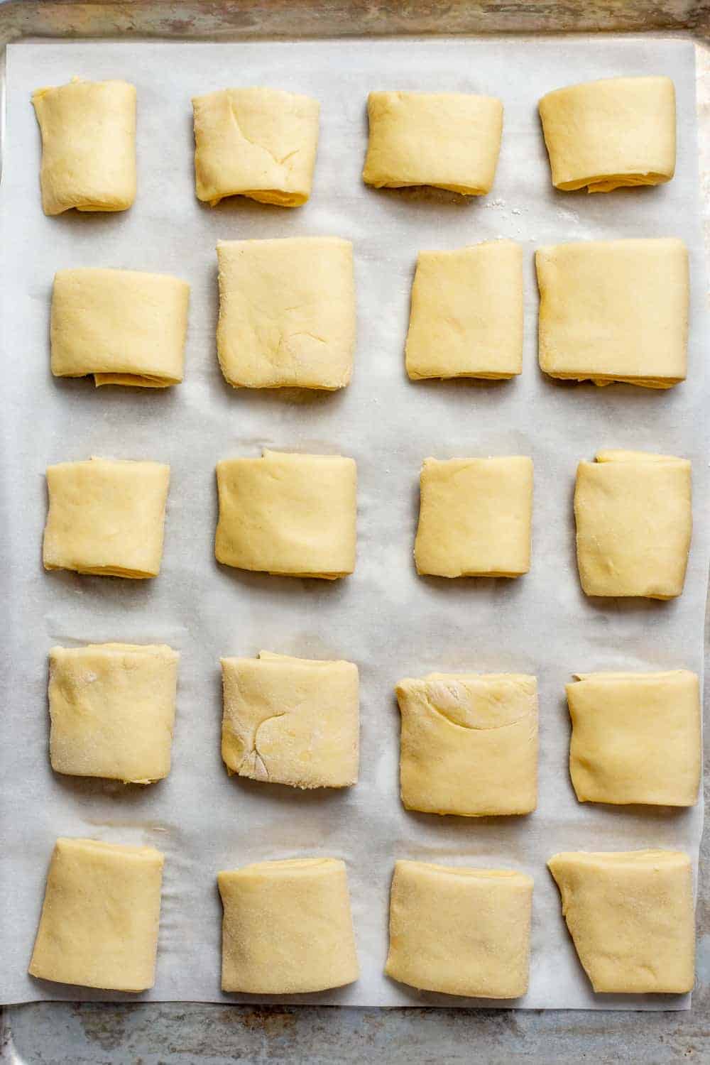 Shaped parker house rolls on a parchment-lined baking sheet