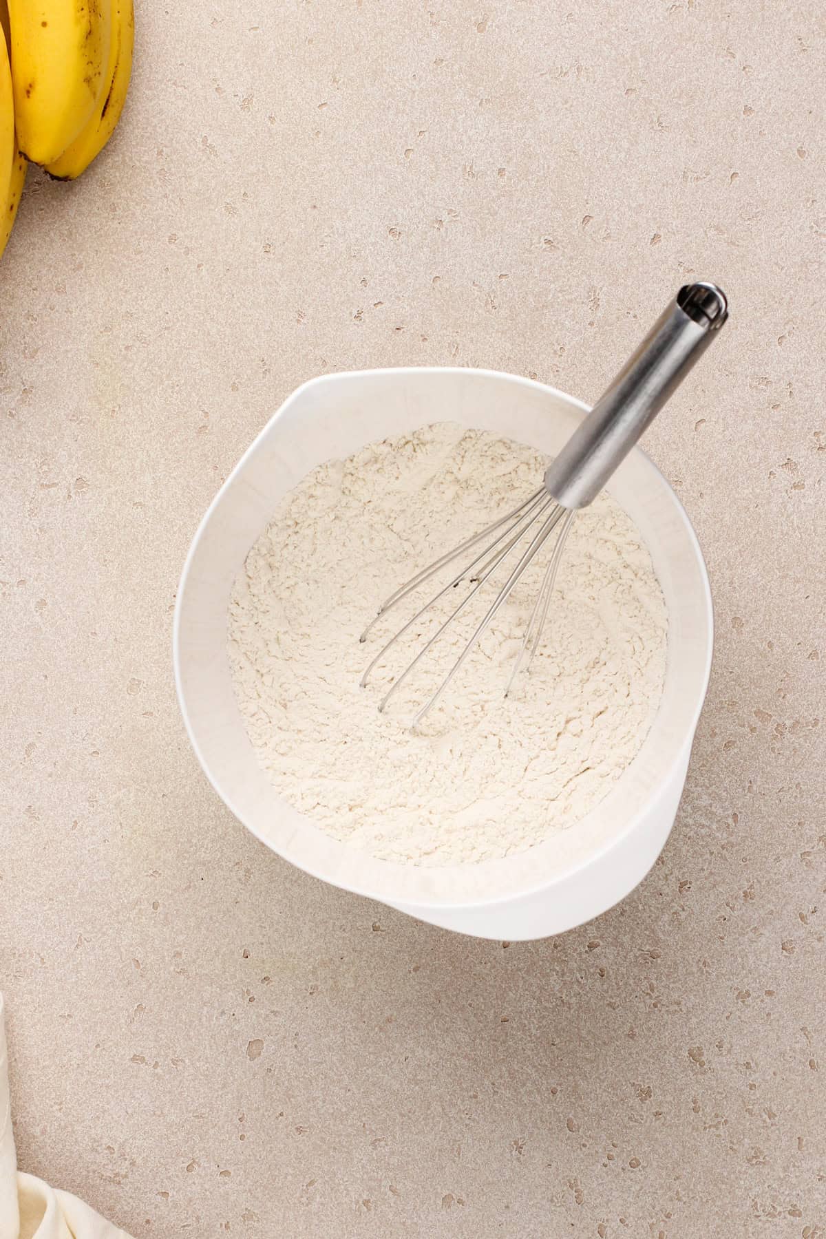 Dry ingredients for peanut butter banana bread whisked together in a white bowl.