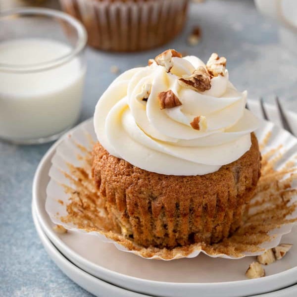 Banana cupcake that has been unwrapped set on a white plate.