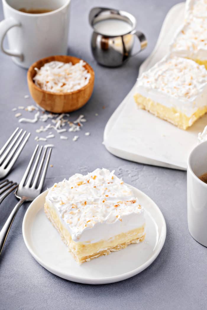 Coconut cream bar on a white plate. More bars are visible in the background.