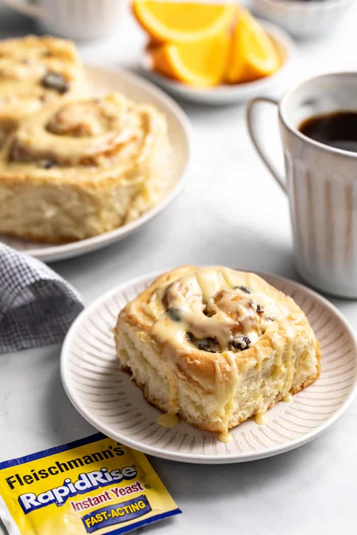 Plated cranberry orange cinnamon roll next to a cup of coffee