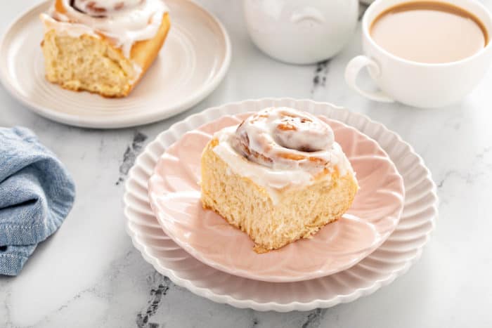 Plated overnight cinnamon rolls next to cups of coffee