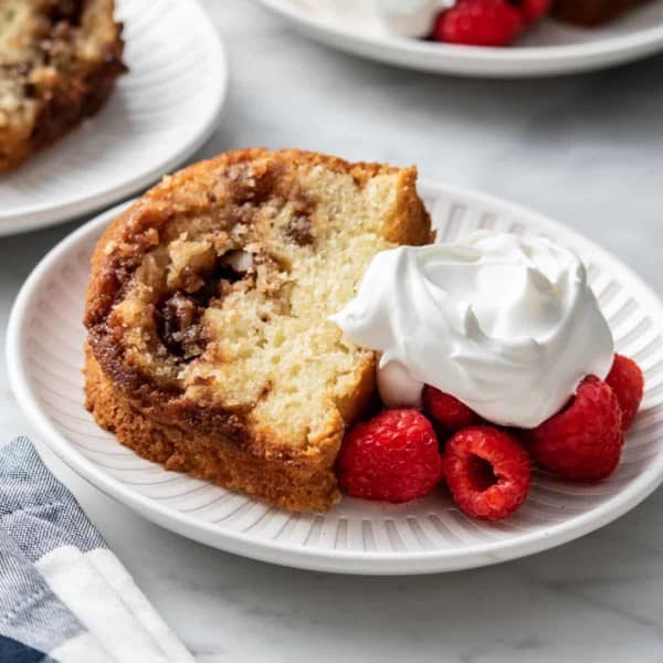 Plated slice of easy coffee cake next to fresh berries and whipped cream.